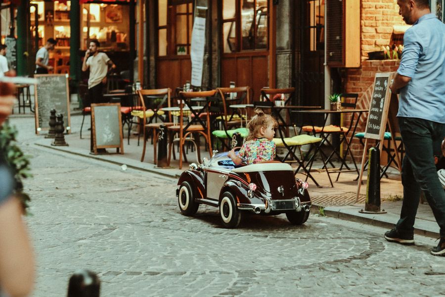 Niño en coche de juguete en calle urbana segura