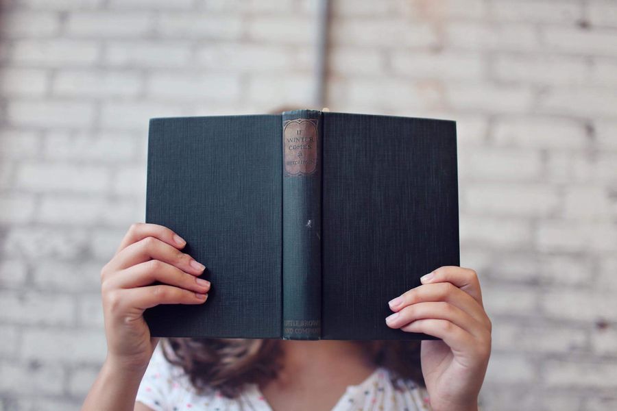 Libro de tapa dura abierto en manos de lectora